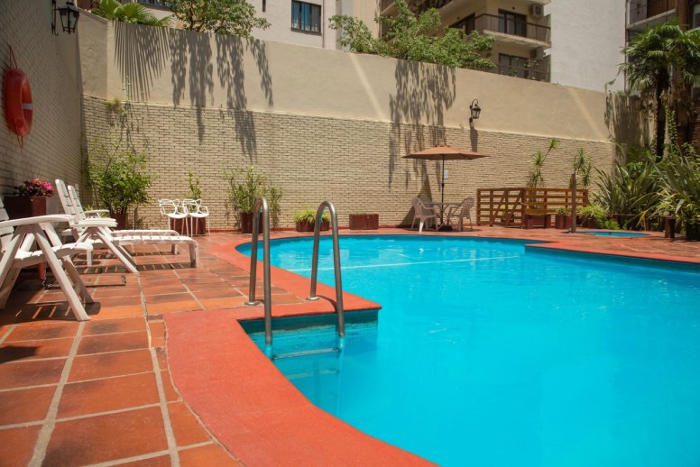 Pileta exterior de temporada con reposeras en Suipacha Suites
